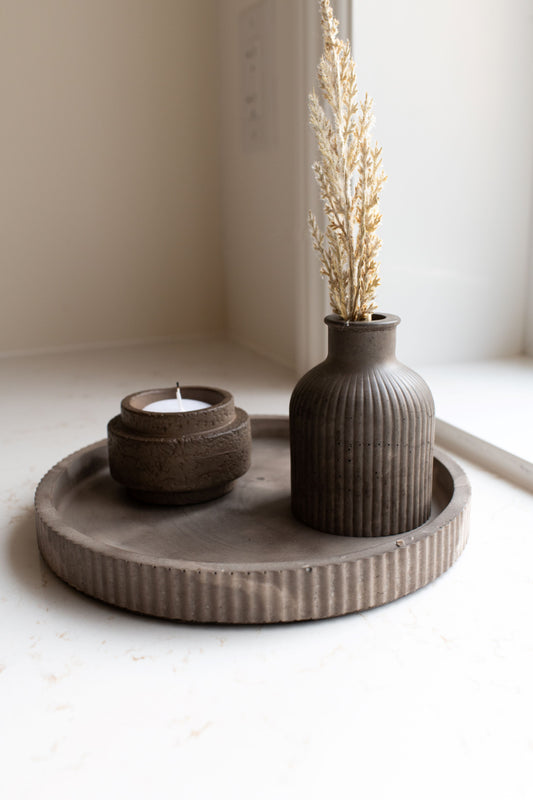 Round mocha tray with bud vase and candle holder on a neutral background.