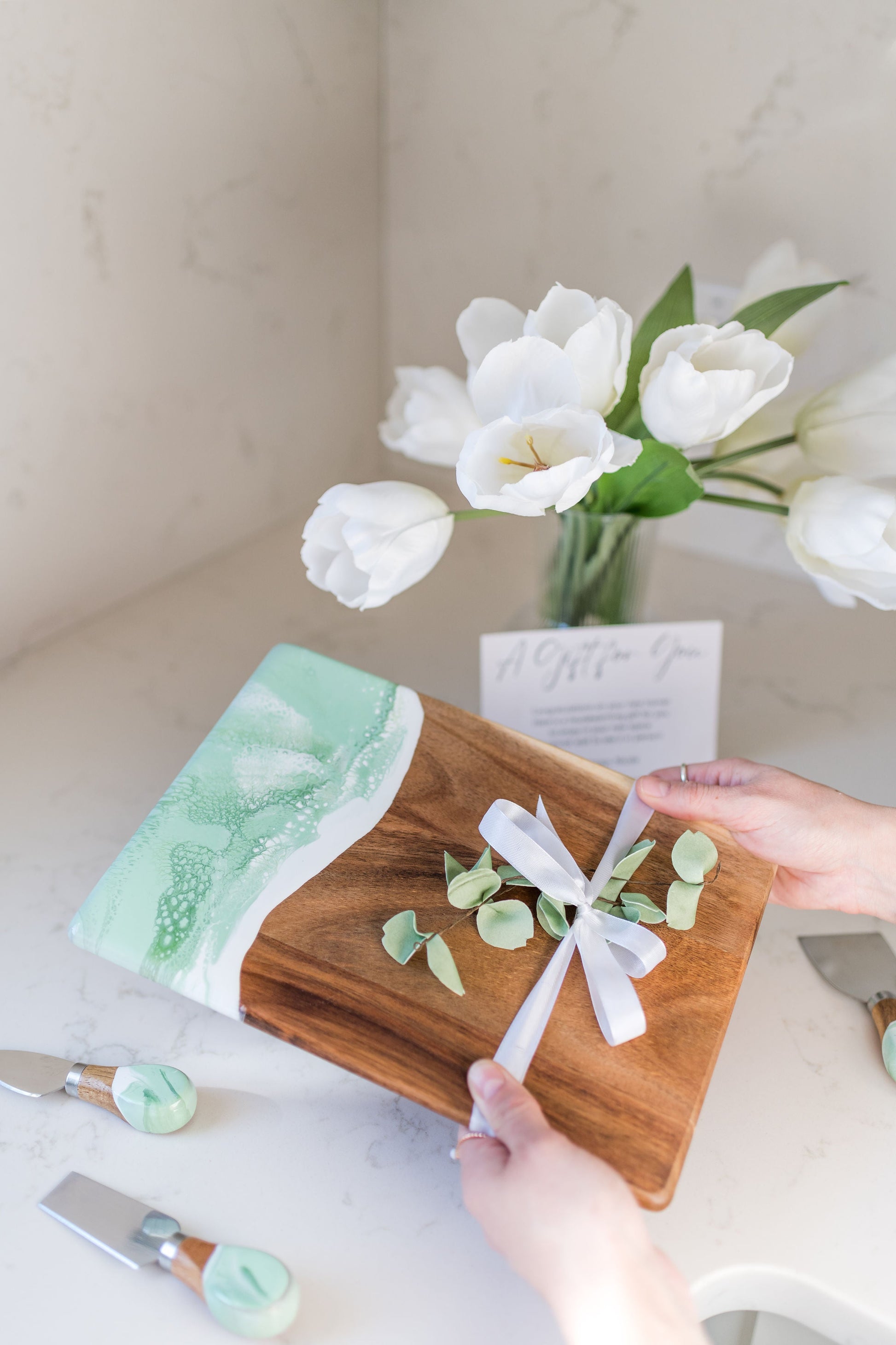mojito date night board with matching cheese knives being held over a kitchen counter