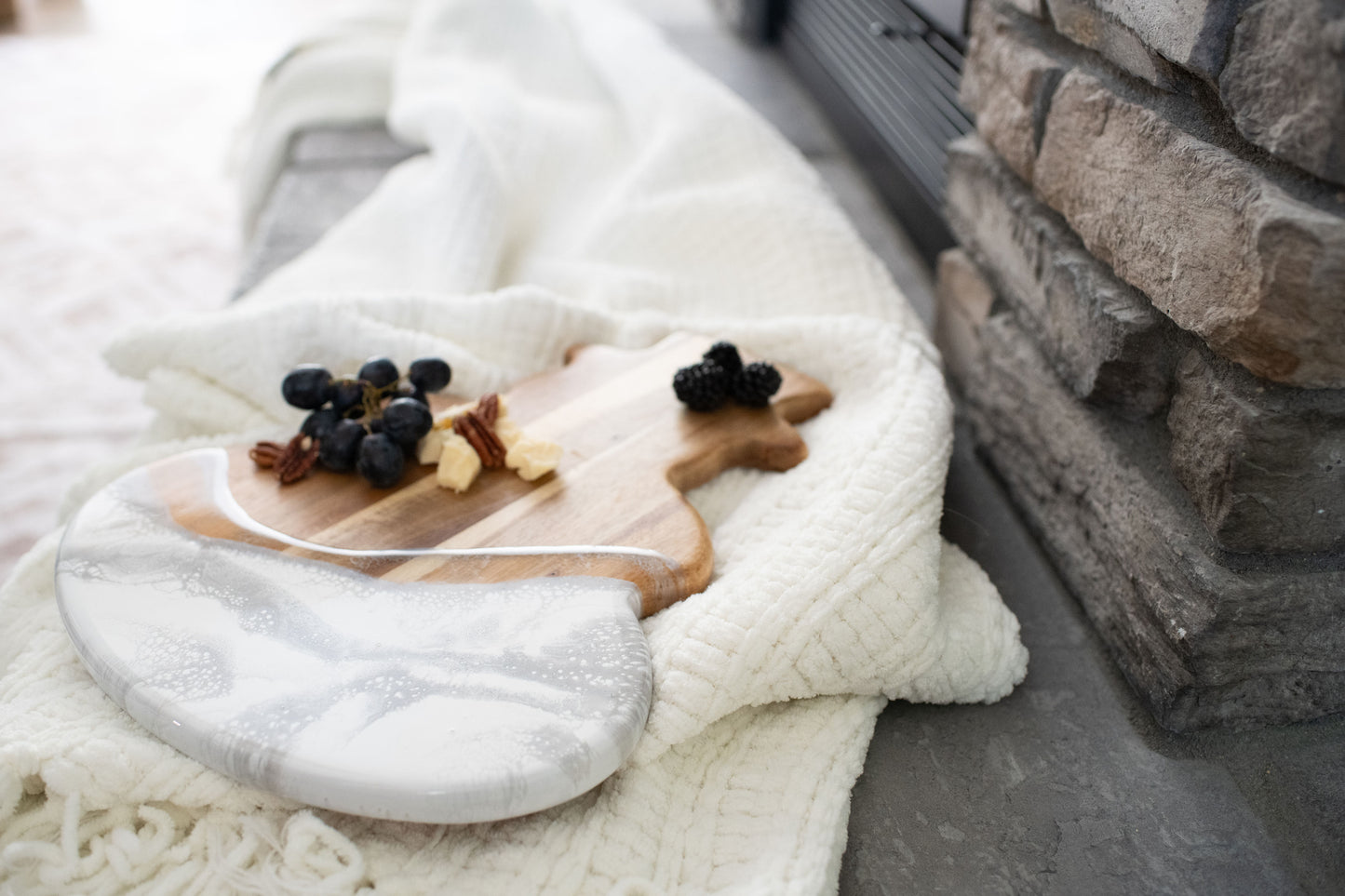 snowman board in the silver metallic resin design placed beside a cozy white blanket by a stone fire place 