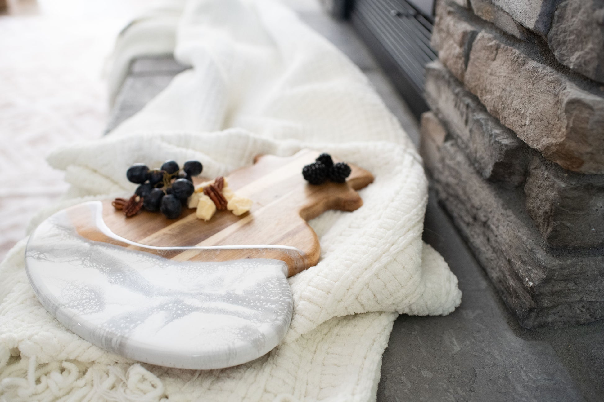snowman board in the silver metallic resin design placed beside a cozy white blanket by a stone fire place 