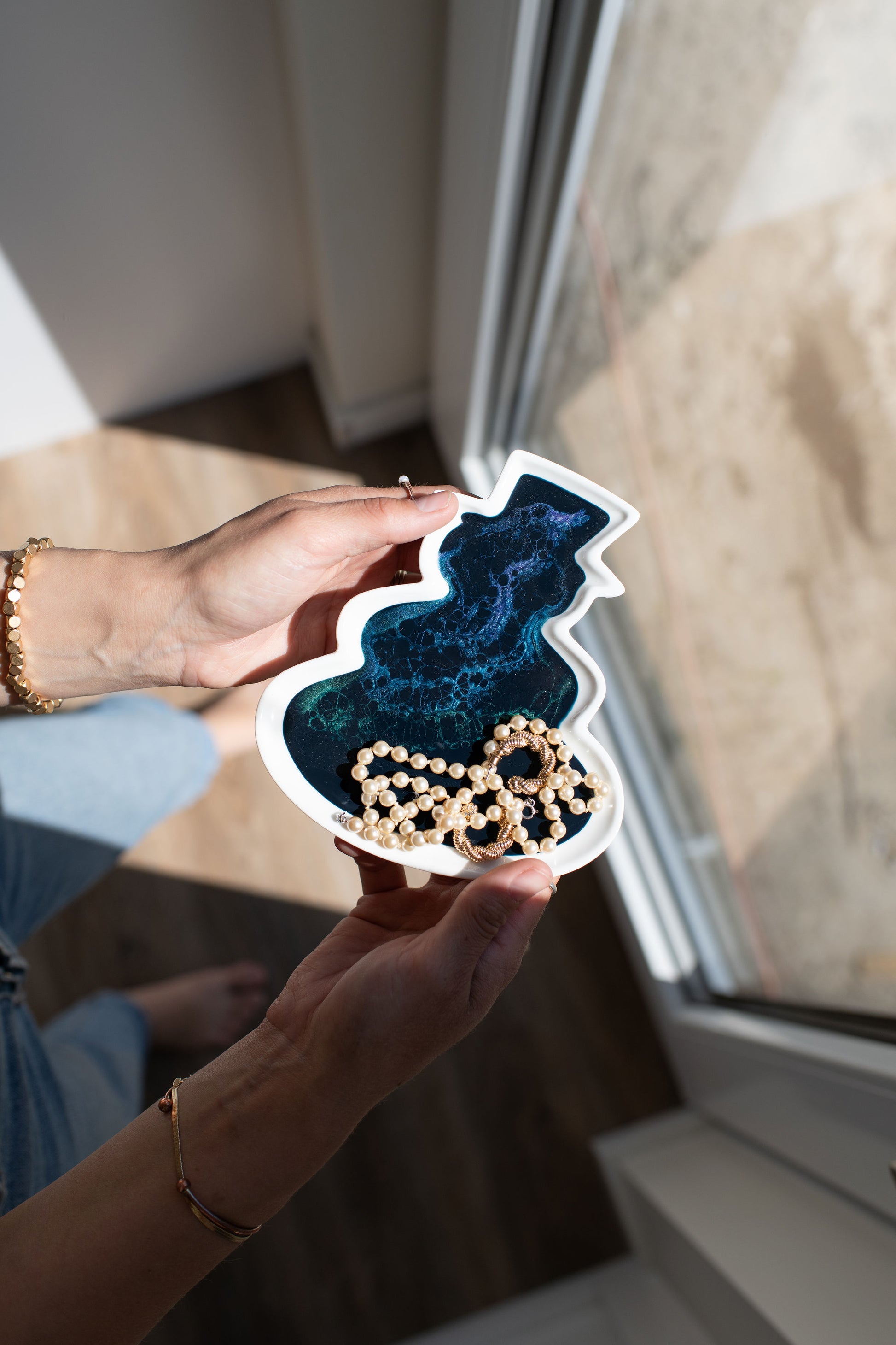 Hands holding a northern lights snowman ceramic tray 