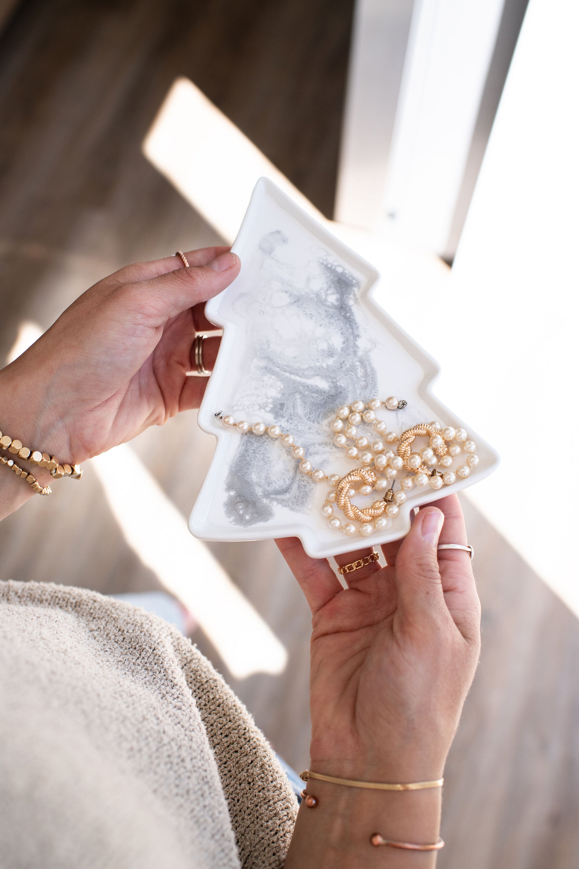 hands holding a Christmas tree shaped ceramic tray with a silver white resin design on it 