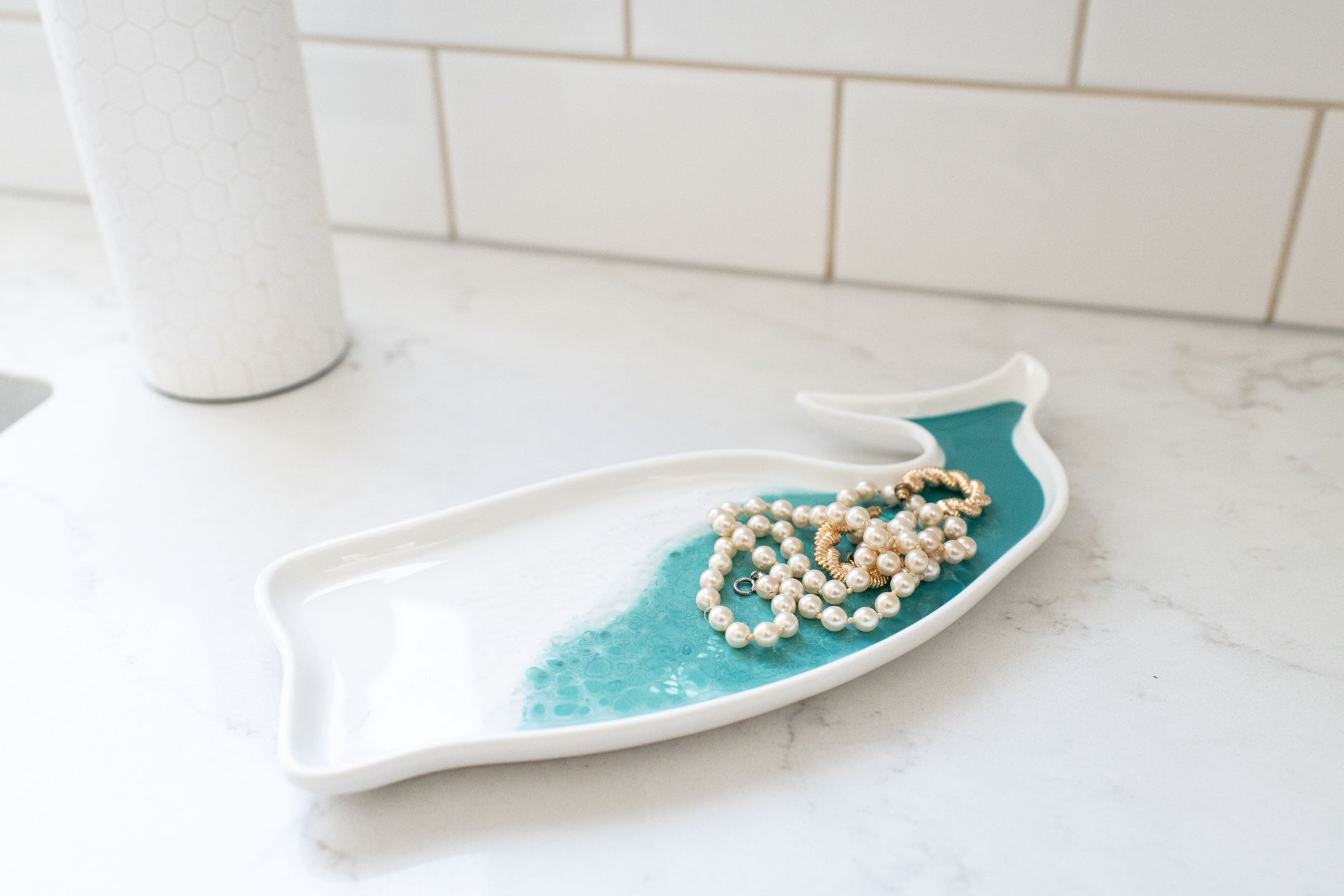 Caribbean blue ceramic whale tray on counter with jewelry on it 
