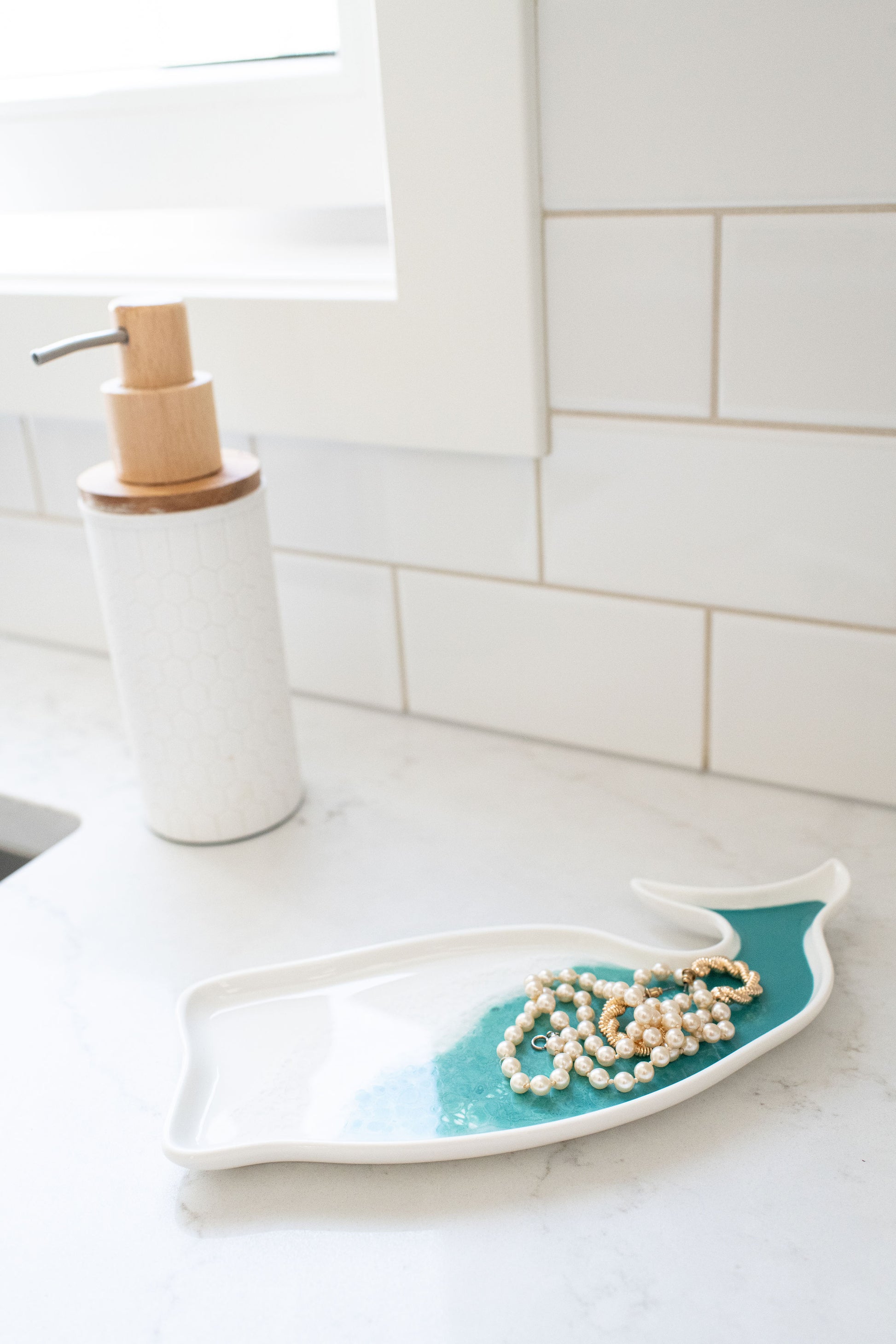 Caribbean blue whale shaped ceramic tray  on kitchen counter with jewelry on it 