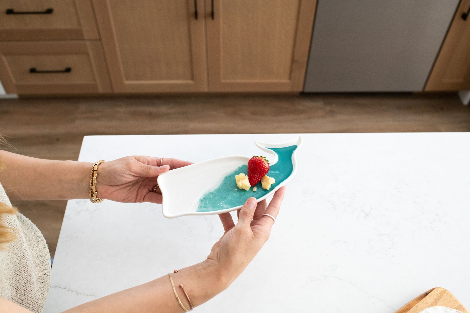 Person holding caribbean blue whale ceramic tray  with a dessert in a kitchen setting