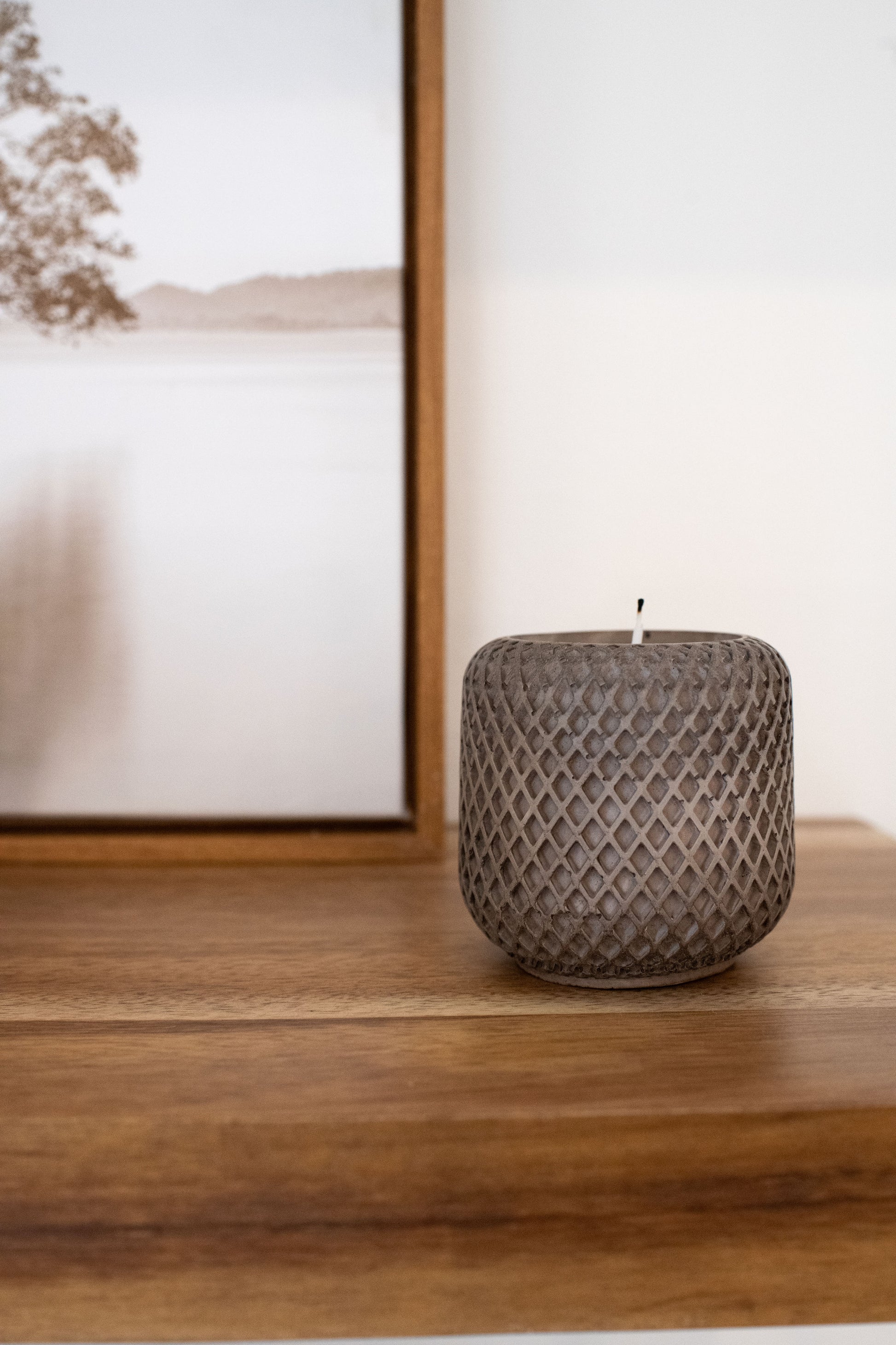 Mocha stone candle holder on a wooden surface with a blurred painting in the background