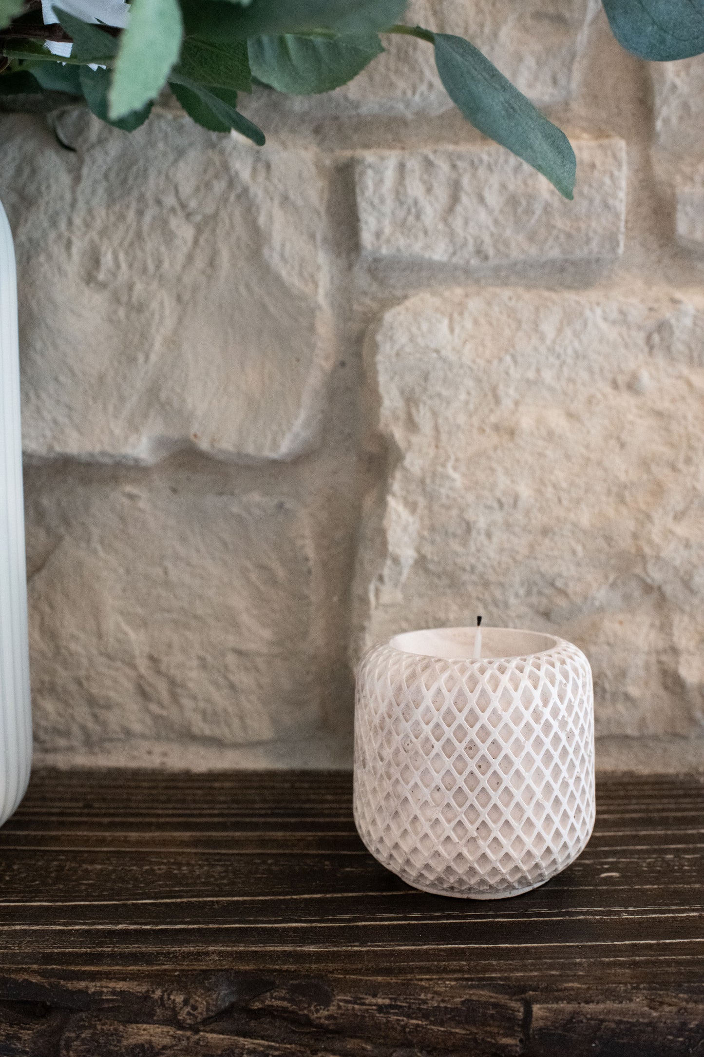 Limestone candle holder on a wooden surface with a stone wall background