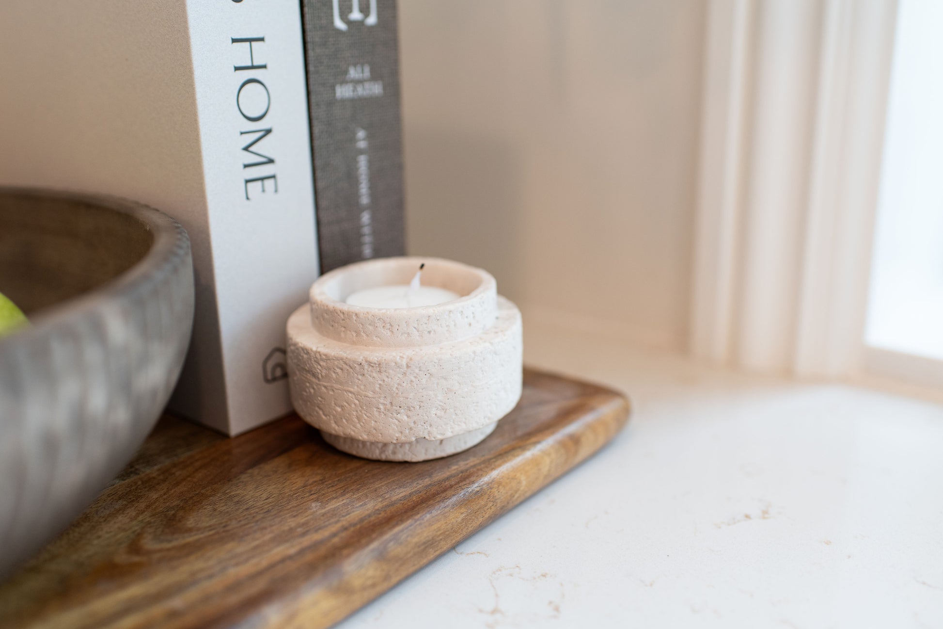 Limestone candle holder displayed on a wooden cutting board and decorative books  