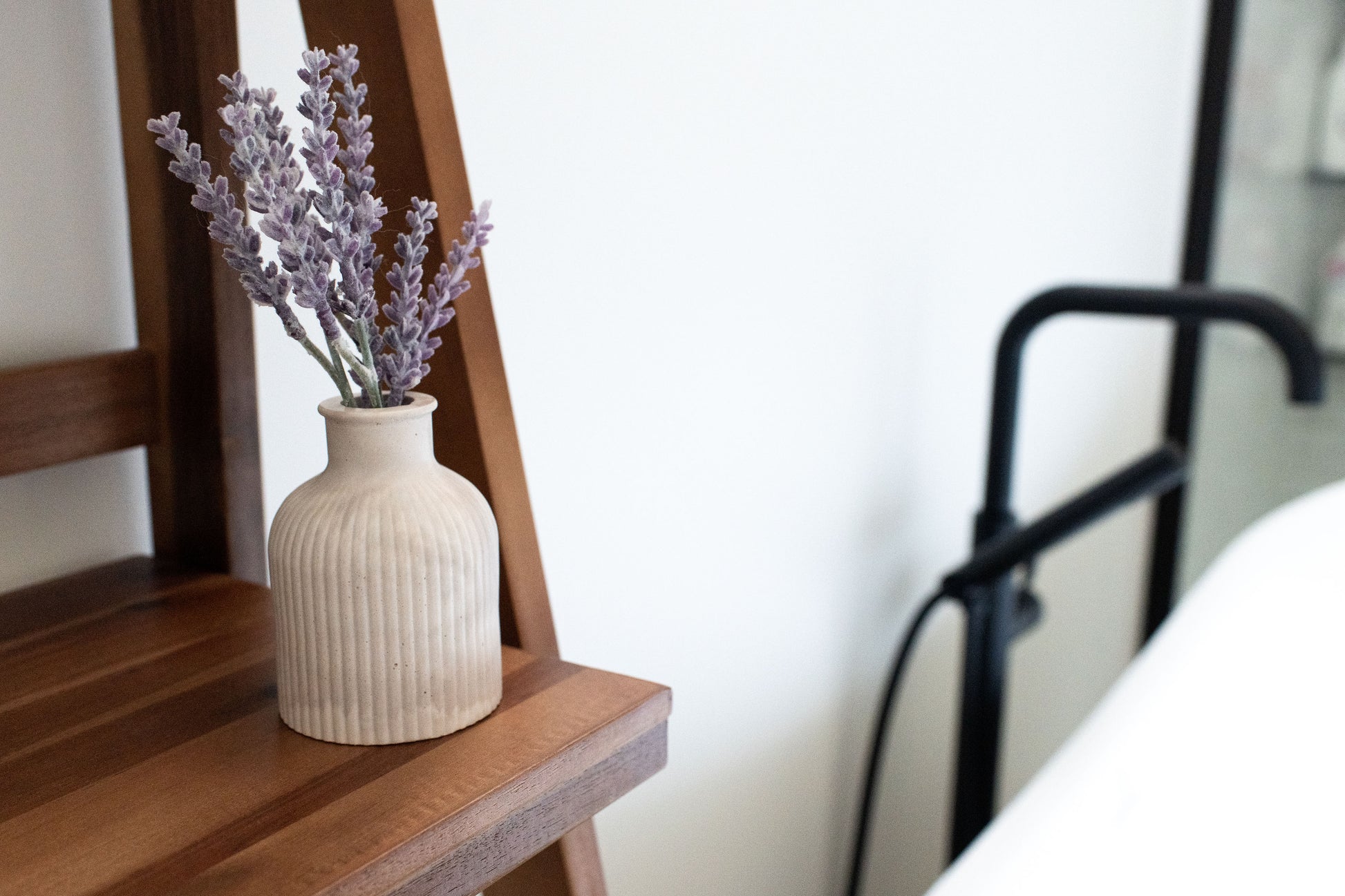 Limestone Budvase on a wooden shelve beside a bathtub 