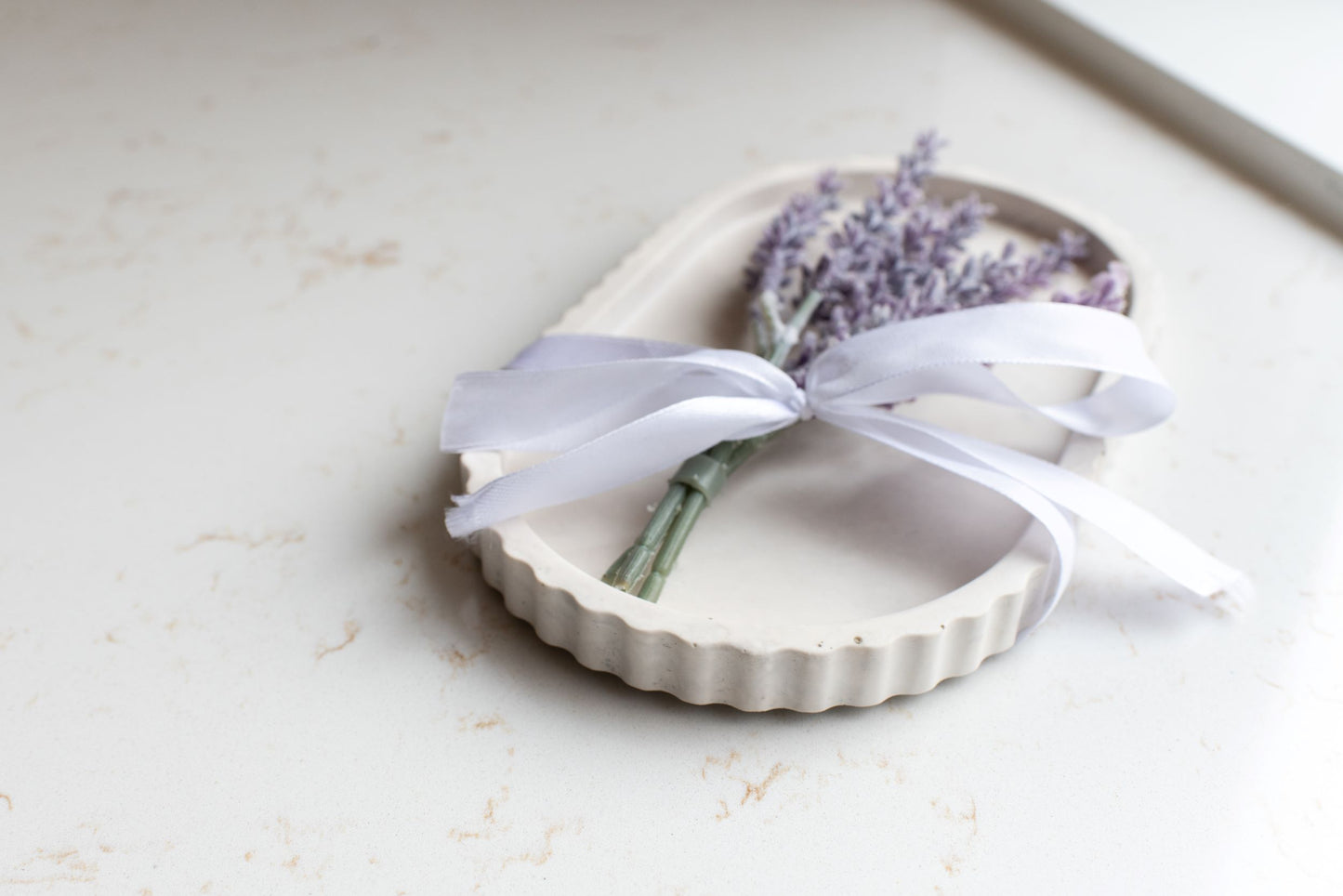 Limestone oval tray with a white bow and lavender stem 