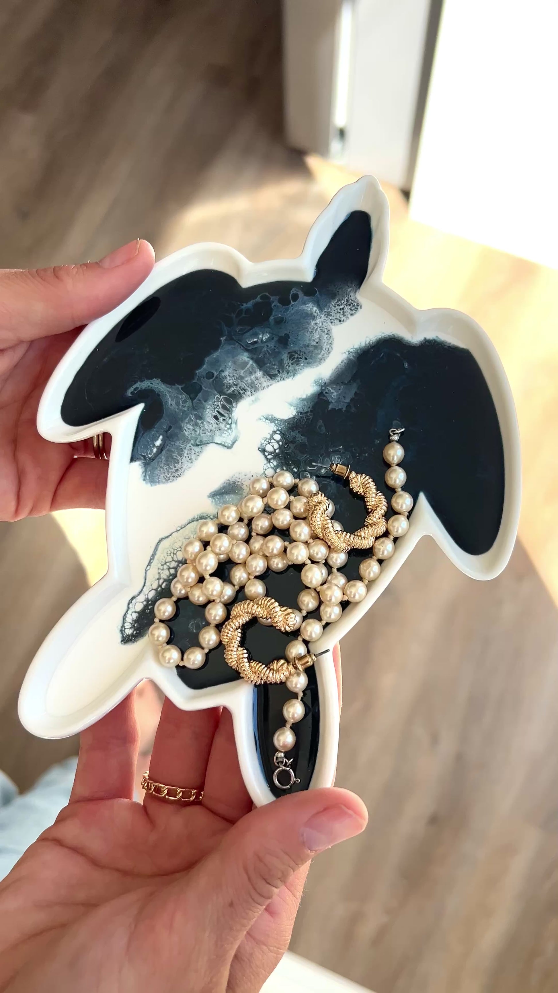 video of a women holding the navy white turtle tray with some jewelry on it 