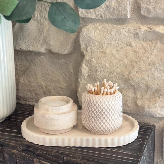 Limestone set of the oval tray , candle holder and match holder displayed on a wooden shelf 