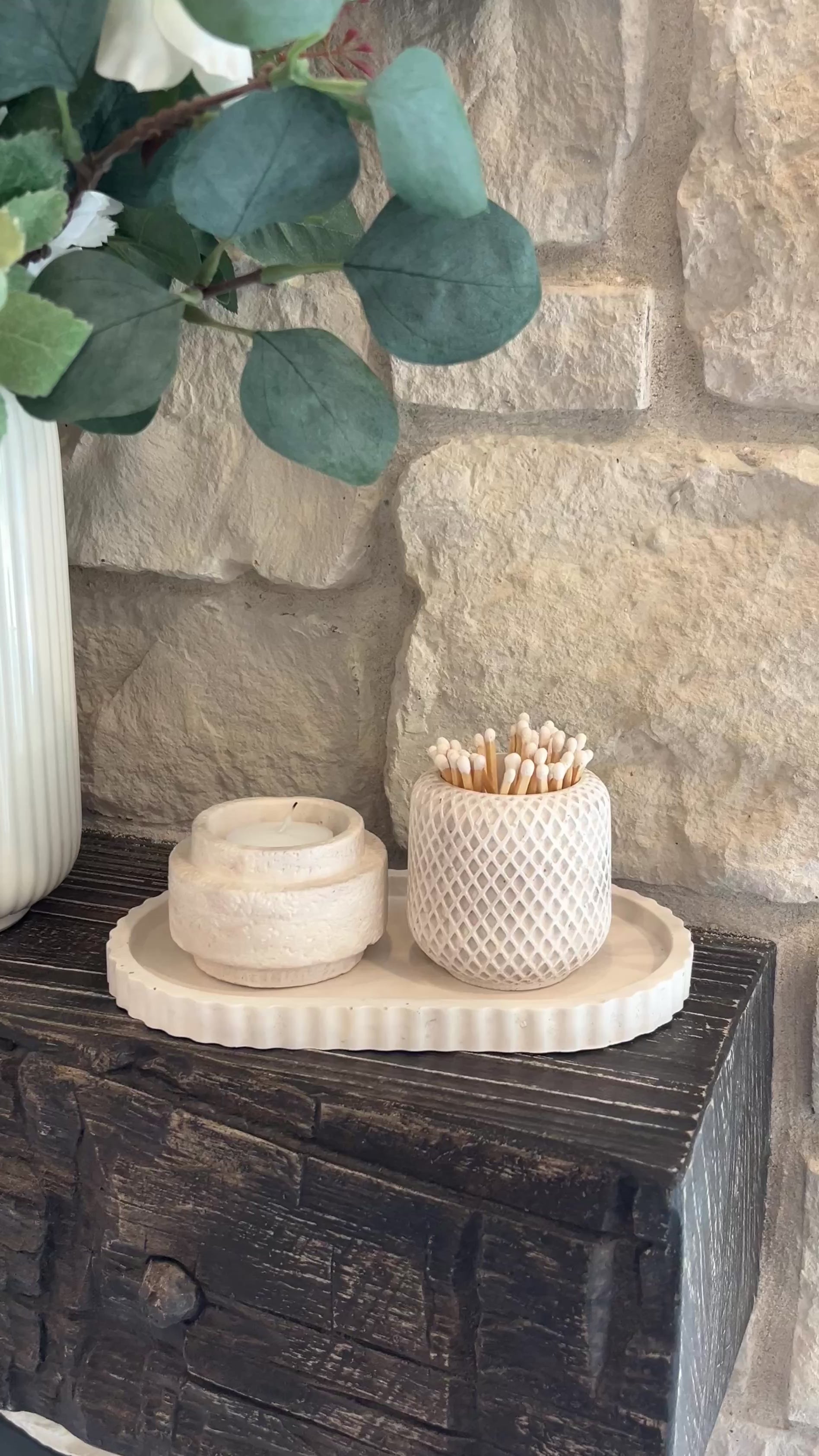 Limestone set of the oval tray , candle holder and match holder displayed on a wooden shelf 